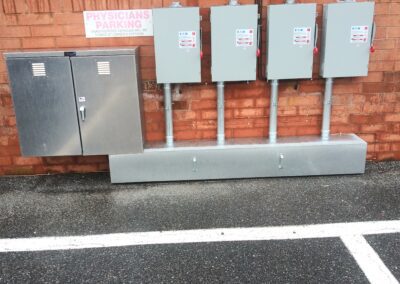 Four electrical boxes and a metal cabinet mounted on a brick wall with a sign above them reading "Physicians Parking.